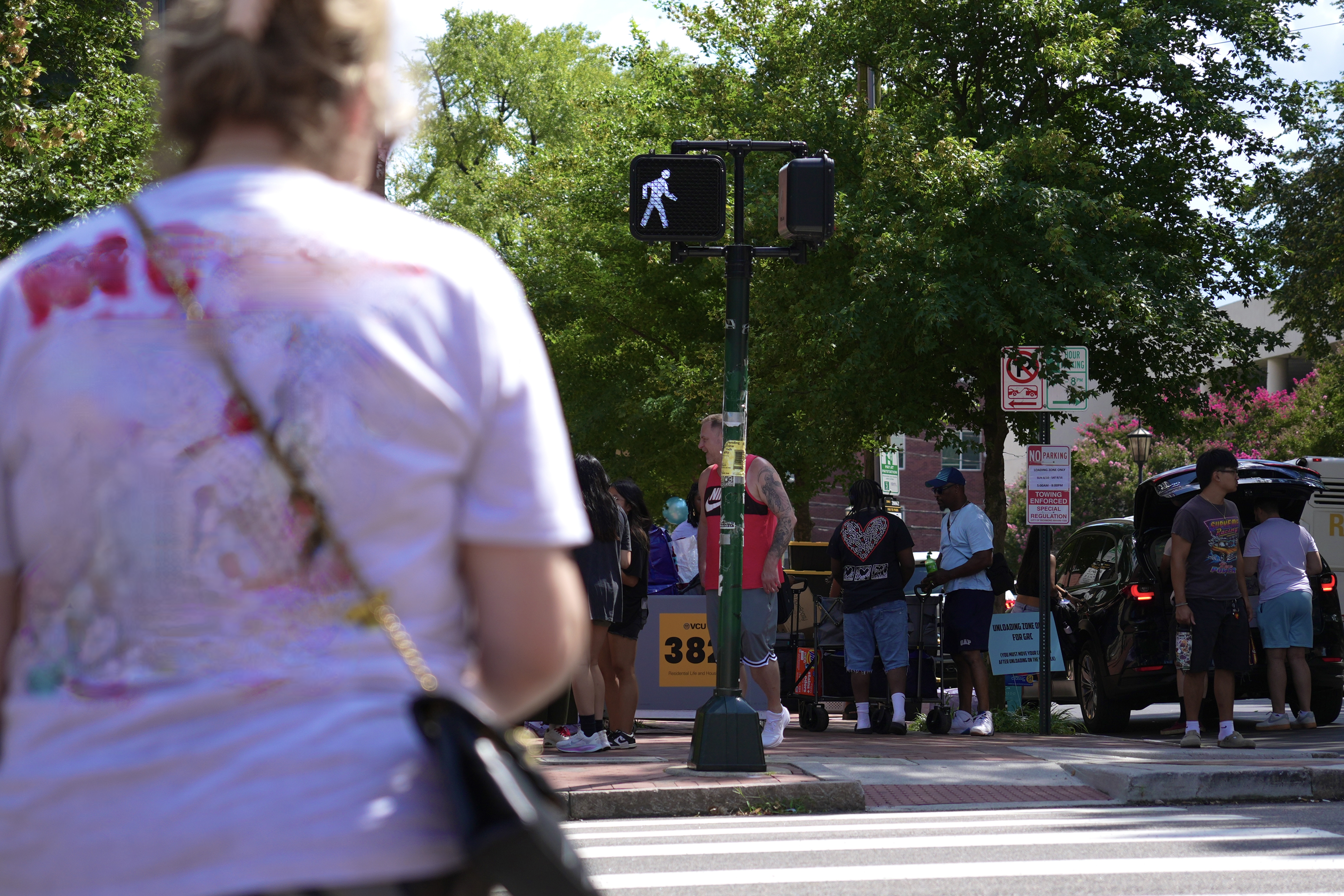 A person walking across a crosswalk with the pedestrian walk sign lit up.