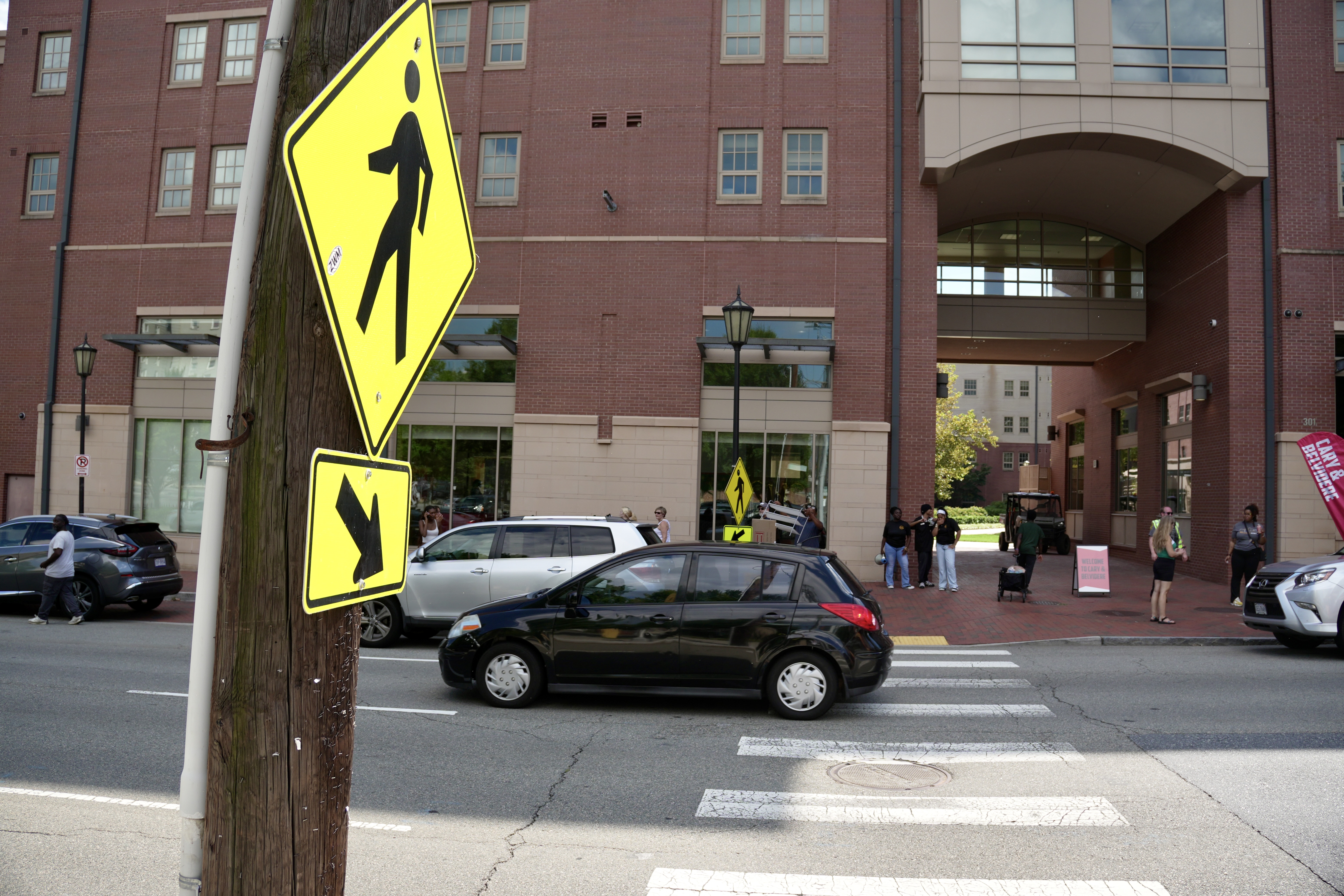 A pedestrian walk sign activated at the intersection of W. Main Street and N. Laurel Street as pedestrians safely walk through the crosswalk.