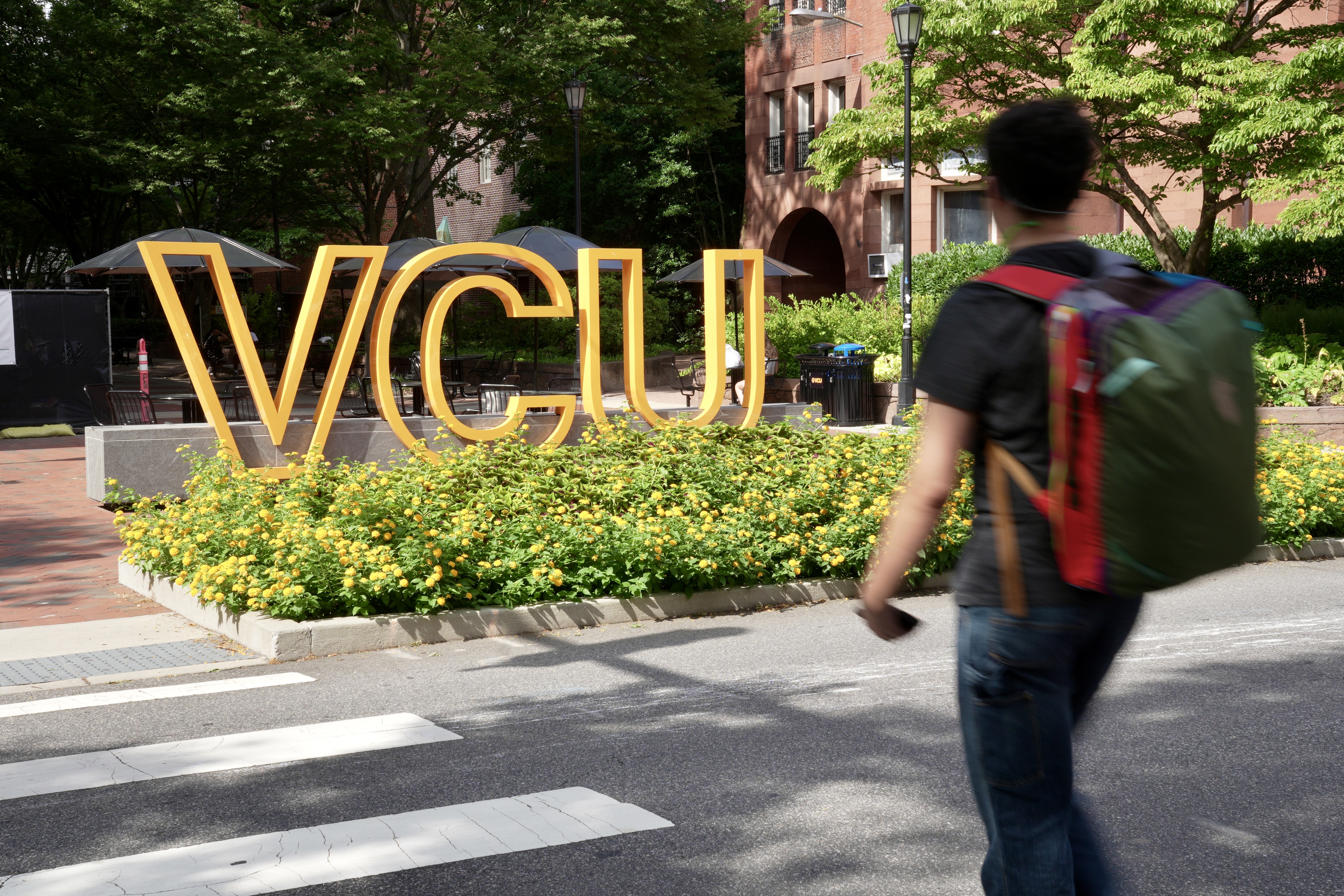 A person wearing a backpack walks across a crosswalk on W. Franklin Street near one of VCU’s “front doors,” which are visual reminders to drivers they are passing through a university campus.