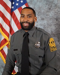 Picture of Officer Christopher Clark in VCU PD uniform, from approximately waist up, sitting in front of an American flag.