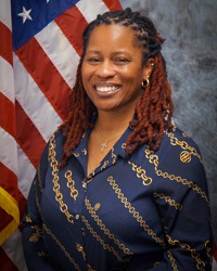 Picture of Detective Cierra Darnell dressed in business casual, from approximately waist up, sitting in front of an American flag.