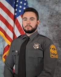 Picture of Officer David Pulliam in VCU PD uniform, from approximately waist up, sitting in front of an American flag.